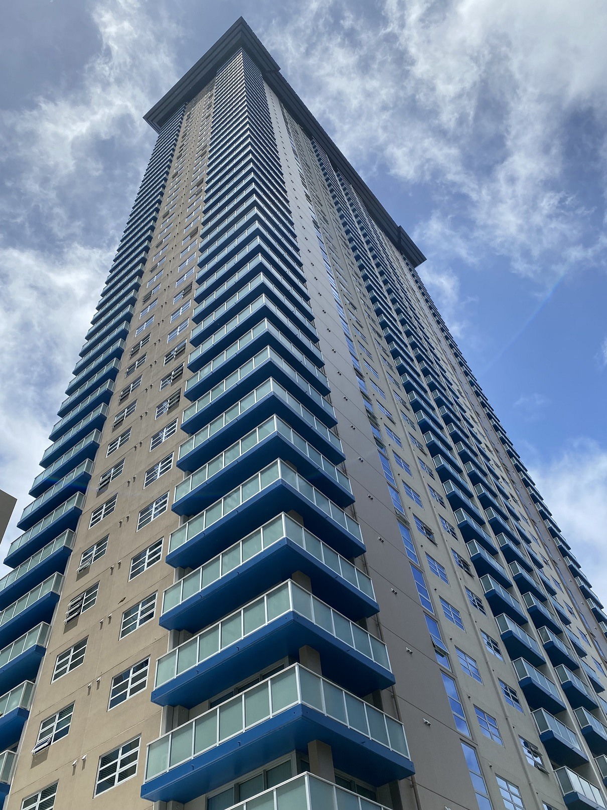 A tall building with blue balconies against a cloudy sky.